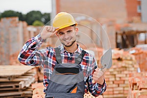 Construction worker man in work clothes and a construction helmet. Portrait of positive male builder in hardhat working