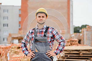 Construction worker man in work clothes and a construction helmet. Portrait of positive male builder in hardhat working