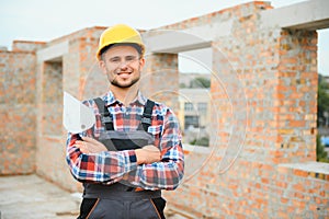 Construction worker man in work clothes and a construction helmet. Portrait of positive male builder in hardhat working