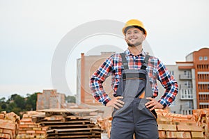 Construction worker man in work clothes and a construction helmet. Portrait of positive male builder in hardhat working