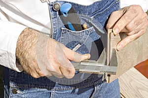 Construction worker measures the thickness of the floor panel by means of the caliper.