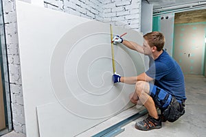 Man measuring plasterboard sheet for interior construction photo