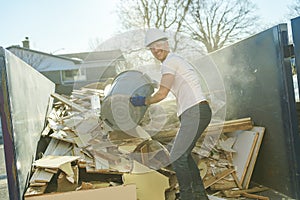 Construction Worker outside of house put old renovation material on big conteiner