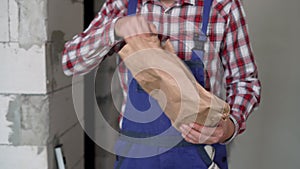 Construction worker in overalls eating burger lunch at workplace