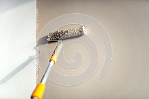 Construction worker painting walls using paint roller. photo