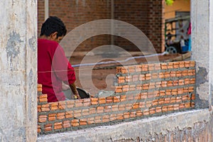 Construction worker placing bricks on cement for building exterior