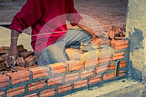 Construction worker placing bricks on cement for building exterior walls