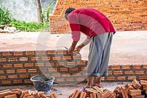 Construction worker placing bricks on cement for building exterior walls