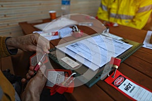 Construction worker placing personal red danger lock which is attached together with danger tag into isolation safety control lock