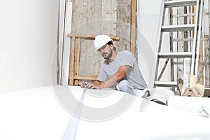 Construction worker plasterer man measuring wall with measure tape in building site of home renovation with tools and building