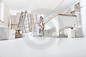 Construction worker plasterer man measuring wall with measure tape in building site of home renovation with tools and building