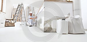 Construction worker plasterer man measuring wall with measure tape in building site of home renovation with tools and building