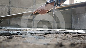 Construction worker or plasterer pour construction cement on floor and leveling concrete floor base by trowel to be smooth. Constr