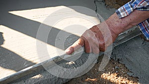 Construction worker or plasterer pour construction cement on floor and levellin concrete floor base by trowel to be smooth. Constr