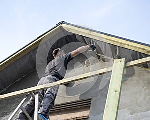 Construction worker plastering the facade of the house