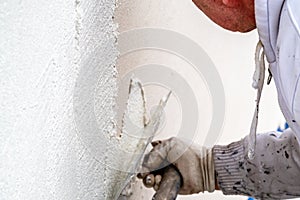 Construction worker plastering and smoothing concrete wall with cement