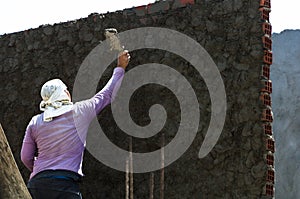 Construction worker - plastering and smoothing concrete wall with cement by a steel trowel - spatula aligns.