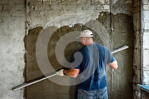 Construction worker plastering wall with leveler