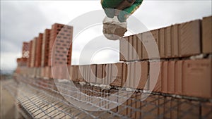Construction worker. Portrait of mason bricklayer installing red brick with trowel putty knife outdoors. Mortar and brick.