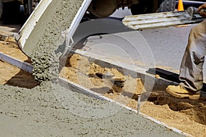 Construction worker pour cement for sidewalk in concrete works with mixer truck with wheelbarrow