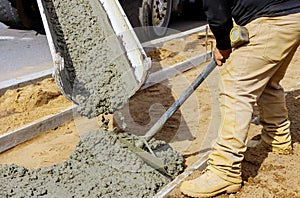 Construction worker pour cement for sidewalk in concrete works with mixer truck with wheelbarrow