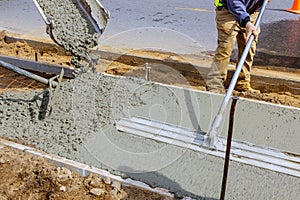 Construction worker pour cement for sidewalk in concrete works with mixer truck with wheelbarrow