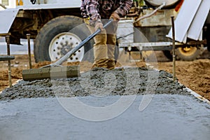 Construction worker pour cement for sidewalk in concrete works with mixer truck with wheelbarrow