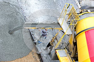 Construction worker pouring concrete from cement truck, people worker