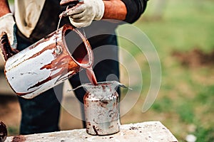 construction worker pouring liquid paint intro spray gun