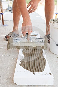 Construction worker puts a gypsum on styrofoam with spatula.