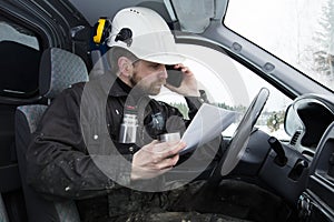 Construction worker reading papers, driving a car and talking on the phone while drinking coffee in Finland.