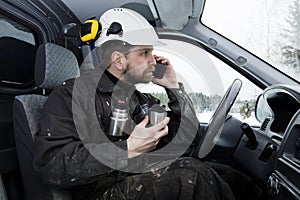 Construction worker reading papers, driving a car and talking on the phone while drinking coffee in Finland.