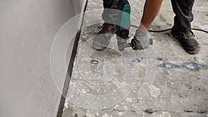 Construction worker removing concrete using rotary hammer drill