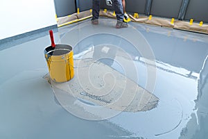 Construction worker renovates balcony floor and spreads watertight resin and glue before chipping and sealing