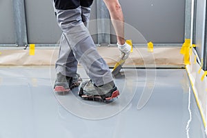 Construction worker renovates balcony floor and spreads watertight resin and glue before chipping and sealing