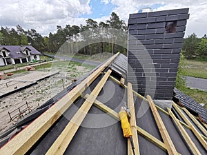 construction worker on a renovation roof covering it with tiles using hammer, crane and grinder