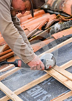 Construction worker cutting with a disc-maker a wood cleat for the implementation of the infrastructure supporting the tiles