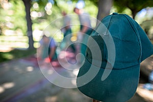 A construction worker's green baseball cap hangs on a wooden peg.