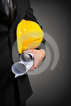 construction worker's hand holding project documents and helmet