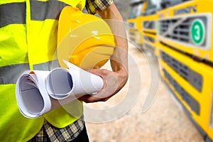 Construction worker's hand holding project documents and helmet