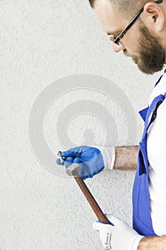 Construction worker`s hands in the protective gloves attach the anchor bolt to the wall of the building.