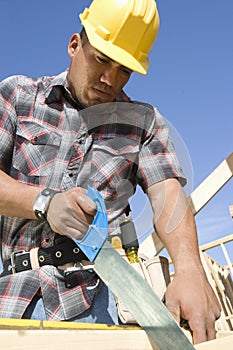 Construction Worker Sawing At Site