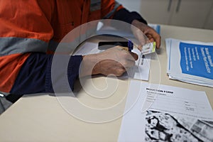 Construction worker setting on a chair holding a pen signing of site safety induction rule and regulation