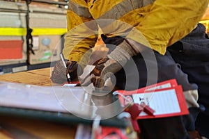 Construction worker setting and writing his name on personnel isolation red danger tag which is attached with personal lock