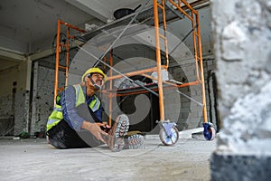 Construction worker sitting with ankle pain on the floor