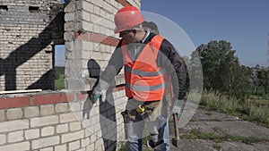 Construction worker with sledgehammer beats brick wall