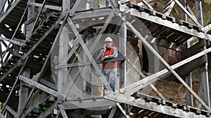 Construction worker with smarth phone on wooden scaffolding