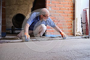 Construction worker smoothing concrete above the radiant underfloor system.