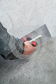 Construction worker smoothing - plastering concrete wall by a st