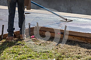 Construction Worker Smoothing Wet Cement With Long Handled Edger Tool photo
